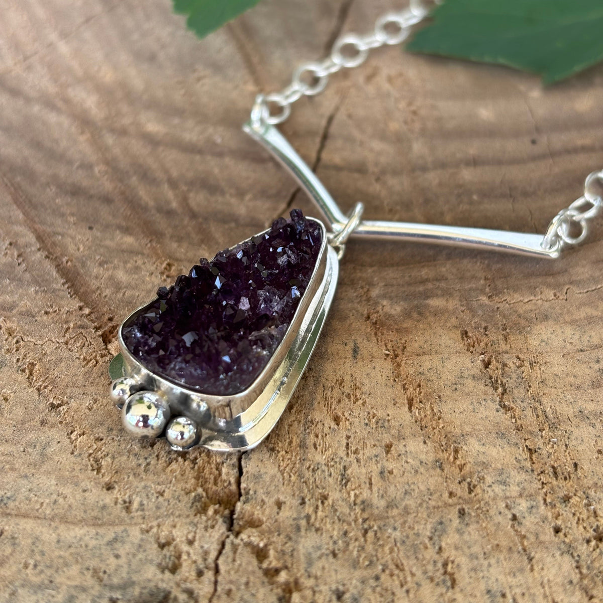 Druzy Amethyst necklace on a wooden surface with a fern leaf