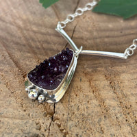 Druzy Amethyst necklace on a wooden surface with a fern leaf
