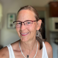 woman with glasses wearing triangular dangle earrings and black druzy necklace