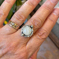 Hand wearing a silver ring with a large moonstone., 