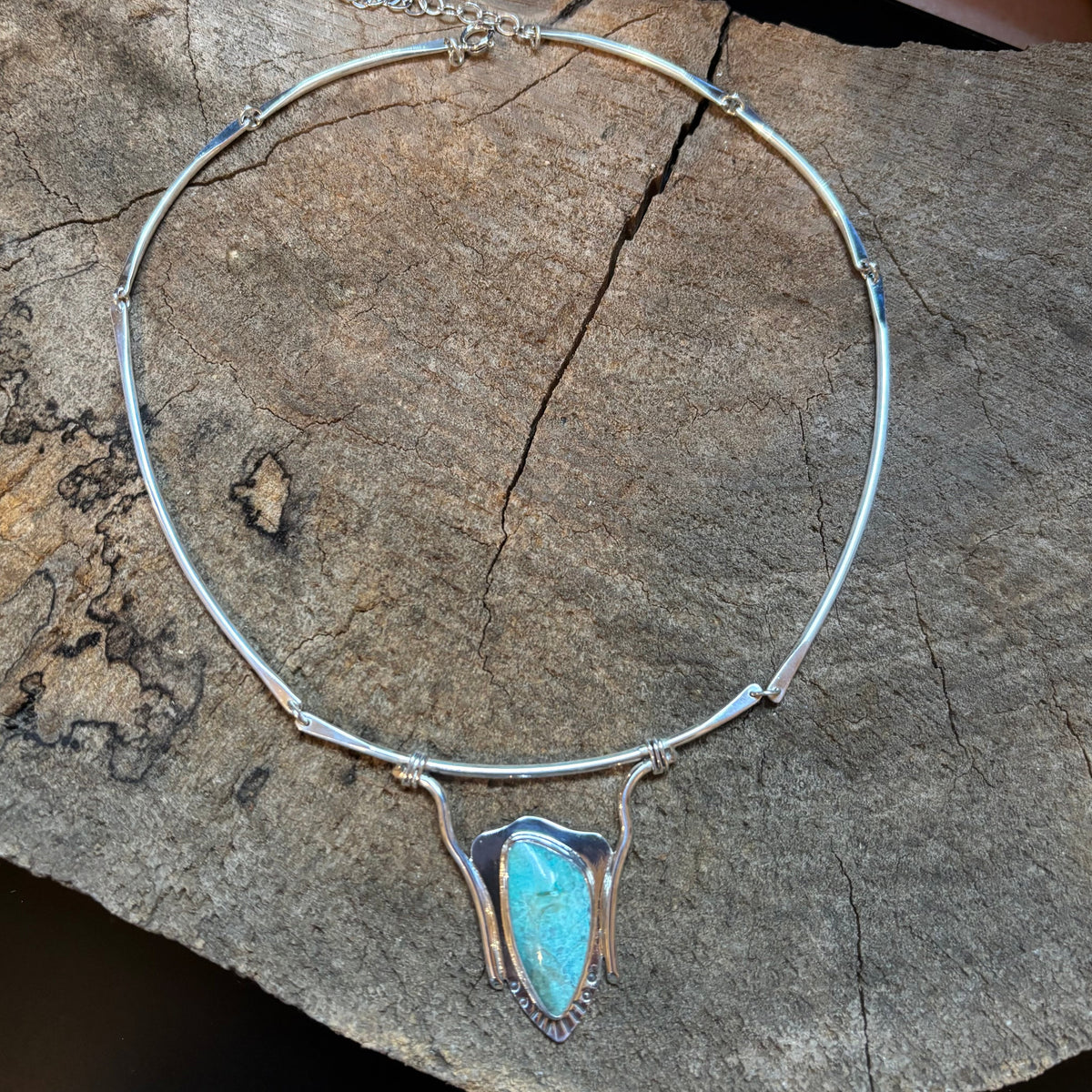 sterling silver and turquoise neck collar on a wood surface
