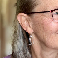 Close-up of a person wearing a silver earring with a blurred background