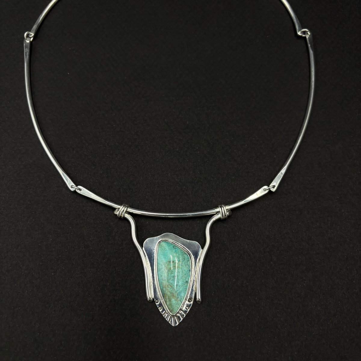 Sterling silver and turquoise neck collar on a black background.