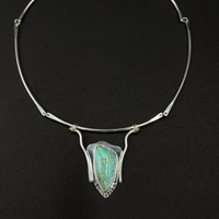 Sterling silver and turquoise neck collar on a black background.