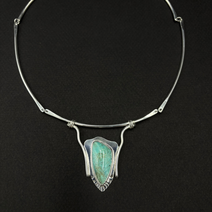 Sterling silver and turquoise neck collar on a black background.